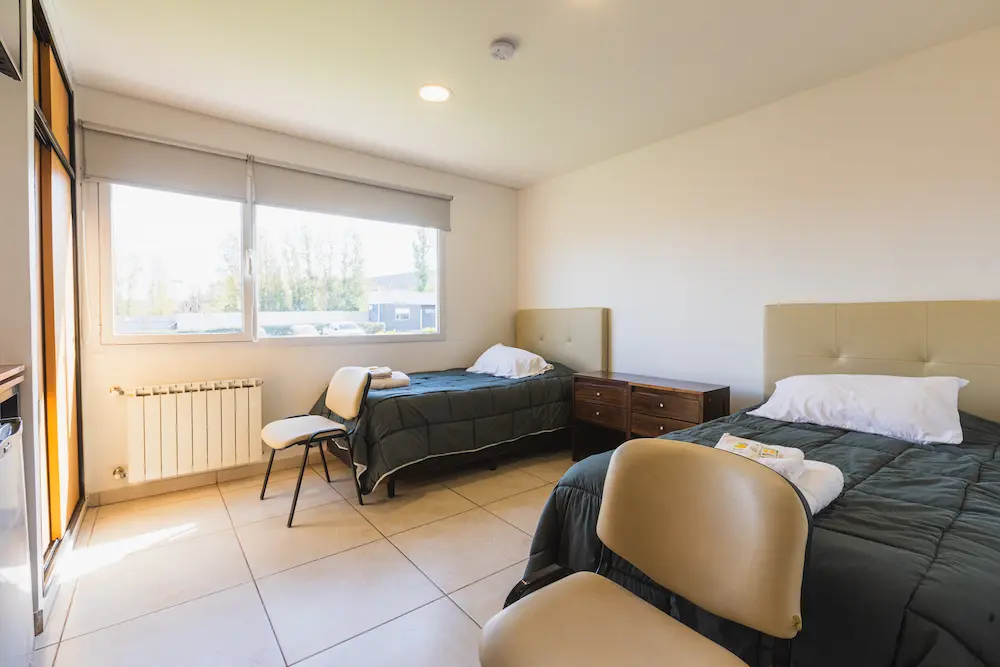 Detalle de la ropa de cama y la mesa de luz de una habitación.